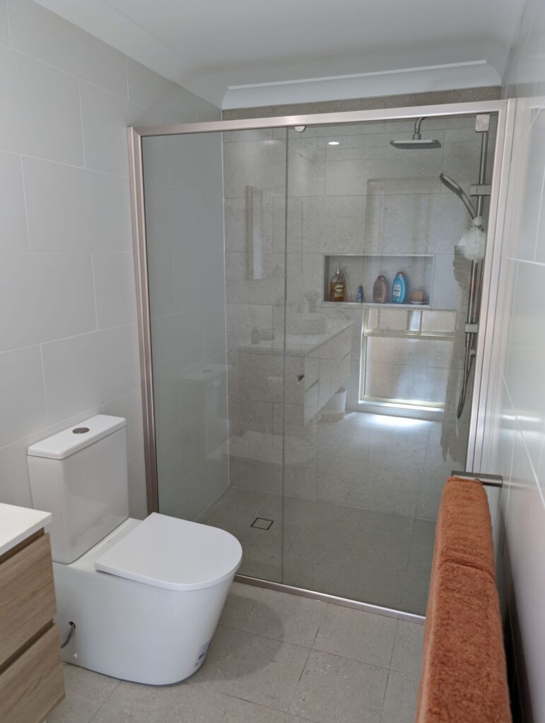 bathroom with glass shower, sink, and toilet